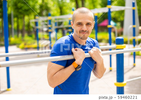Athletic man leaning on bars and looking in camera Athletic man leaning on bars and looking in camera 59460221