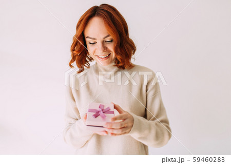 Young festive girl smiles, peeking inside a gift box. Young festive girl smiles, peeking inside a gift box. 59460283