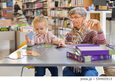 Granddaughter and grandmother put together a puzzle in the city library 59460913