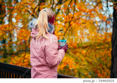 Adult blond woman holds a cup of herbal tee in hands in beautiful autumn forest golden leaves in Adult blond woman holds a cup of herbal tee in hands in beautiful autumn forest golden leaves in 59460928