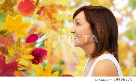 profile of smiling senior woman over autumn leaves profile of smiling senior woman over autumn leaves 59466276
