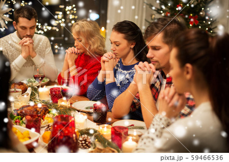 friends having home christmas dinner and praying 59466536