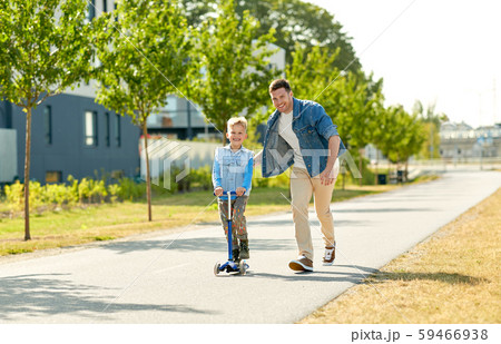 happy father and little son riding scooter in city 59466938