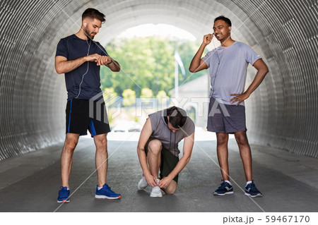 male friends with earphones training outdoors 59467170