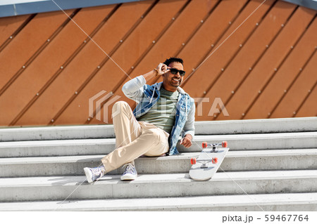 indian man with skateboard sitting on city stairs 59467764
