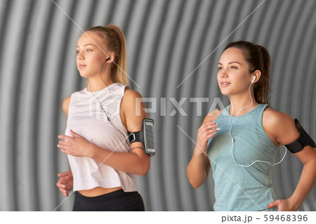 young women with earphones and smartphones running young women with earphones and smartphones running 59468396