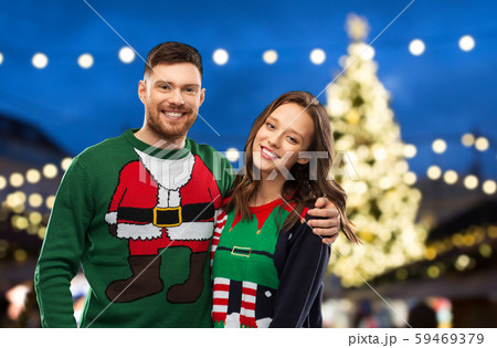 happy couple in ugly sweaters at christmas market 59469379