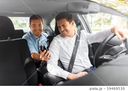 male passenger showing smartphone to car driver male passenger showing smartphone to car driver 59469530