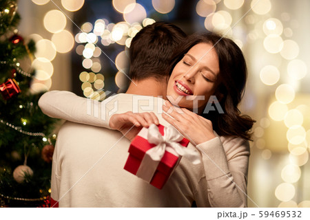 happy couple with christmas gift hugging at home 59469532