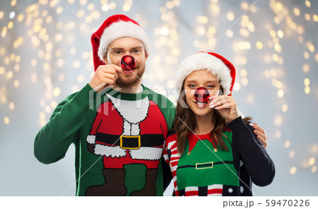 happy couple in christmas sweaters and santa hats happy couple in christmas sweaters and santa hats 59470226