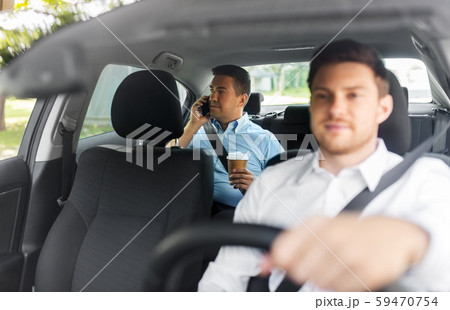 male passenger with coffee calling on phone in car 59470754