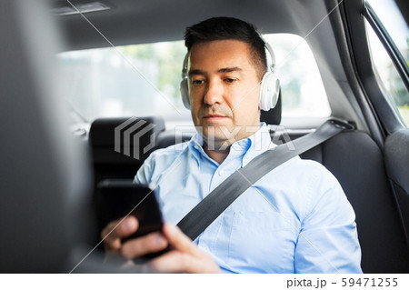 passenger with headphones using smartphone in car 59471255