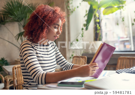 Red-haired young pretty businesswoman reading business literature 59481781