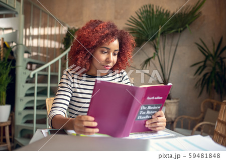 Promising young businesswoman reading business book attentively 59481848