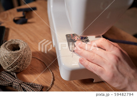 Tailor makes bow ties of woolen fabric. Work with sewing machine in a textile studio. 59482794