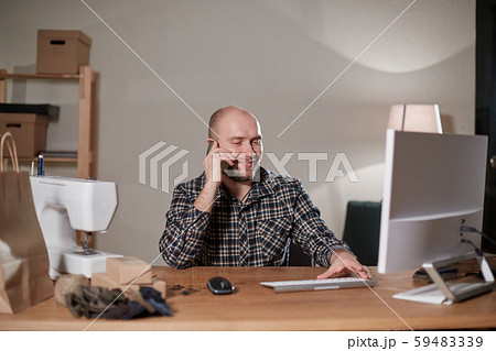 Happy man speak by phone. On the computer makes out the delivery of the online store. Working with 59483339