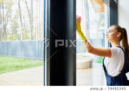 Side view on young cleaner in uniform cleaning Side view on young cleaner in uniform cleaning 59483340