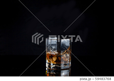 Whiskey splash from the fallen ice cube into glass Whiskey splash from the fallen ice cube into glass 59483768