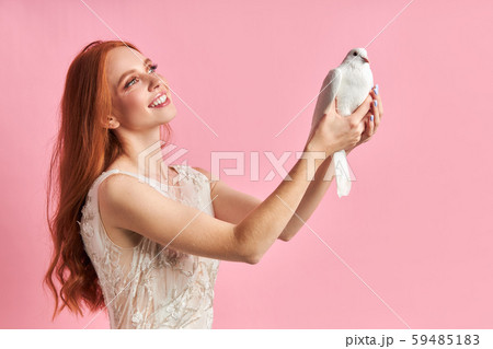 Smiling cute female holding white dove and look with love Smiling cute female holding white dove and look with love 59485183