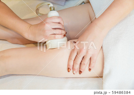 Body massage with cavitation. Young girl on massage table anti cellulite massage Body massage with cavitation. Young girl on massage table anti cellulite massage 59486384