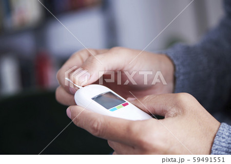 man about to measure his blood glucose level. 59491551