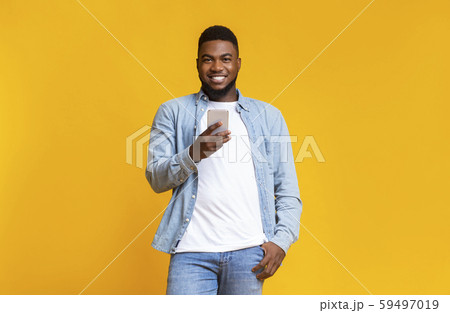 Handsome african man holding phone and smiling at camera 59497019