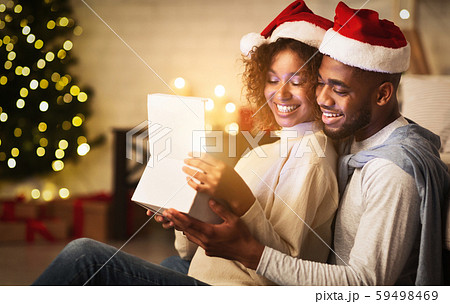 Xmas magic. Cute couple opening Christmas gift box Xmas magic. Cute couple opening Christmas gift box 59498469