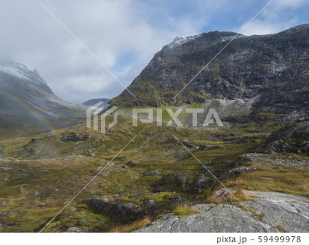 Lake Alnesvatnet with snow capped mountain peak and rainbow. View from scenic road 63 in the 59499978