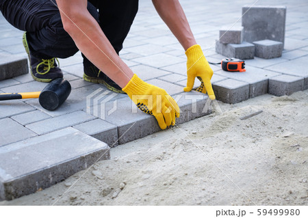 The master in yellow gloves lays paving stones 59499980