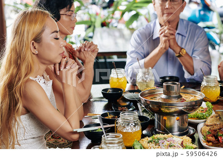 Pretty woman praying before dinner with family Pretty woman praying before dinner with family 59506426