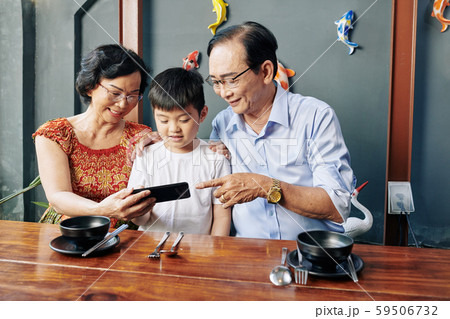 Senior people showing mobile app to grandson Senior people showing mobile app to grandson 59506732