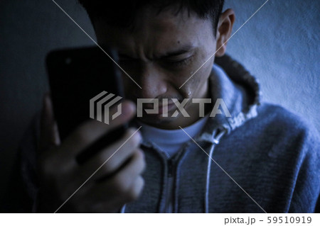 スマートフォンを手に持ち涙を流す男性 59510919