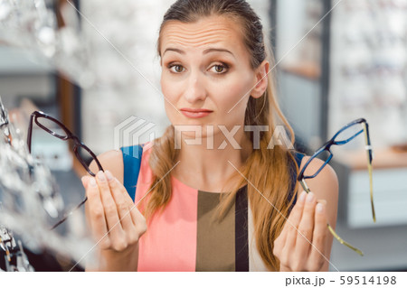 Woman choosing between two models of glasses at optometrist Woman choosing between two models of glasses at optometrist 59514198