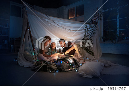 Family sitting in a teepee, reading stories with the flashlight Family sitting in a teepee, reading stories with the flashlight 59514767