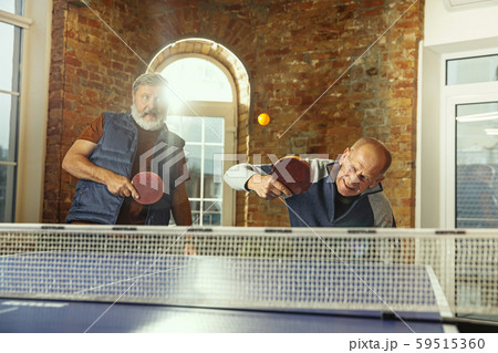 Senior men playing table tennis in workplace, having fun Senior men playing table tennis in workplace, having fun 59515360