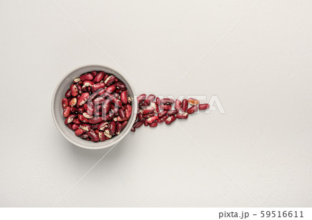 Bowl with red beans on a light textured background. Next to the grain is poured in the form of an 59516611