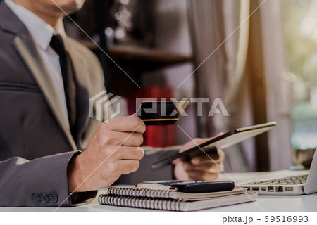 Businessman hold credit cards, conduct financial transactions via tablets and data documents, put on the desk in the morning. Businessman hold credit cards, conduct financial transactions via tablets and data documents, put on the desk in the morning. 59516993