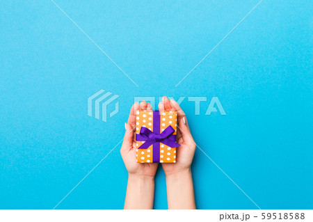 Woman arms holding gift box with colored ribbon on 59518588