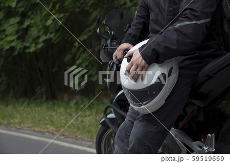 Driver riding motorcycle on an asphalt road through forest. 59519669