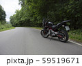 Driver riding motorcycle on an asphalt road through forest. 59519671