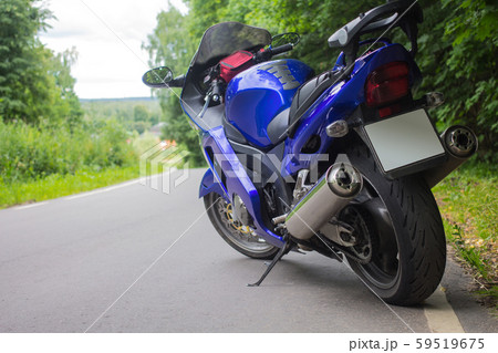 Driver riding motorcycle on an asphalt road through forest. 59519675