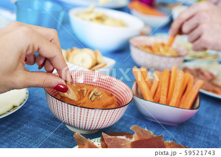 people having some appetizers on a colorful table. 59521743