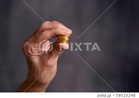 Coins held by fingers. Gold coins in a hand 59523246