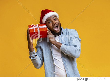 Crazy black guy in Santa hat holding Christmas gift box Crazy black guy in Santa hat holding Christmas gift box 59530838