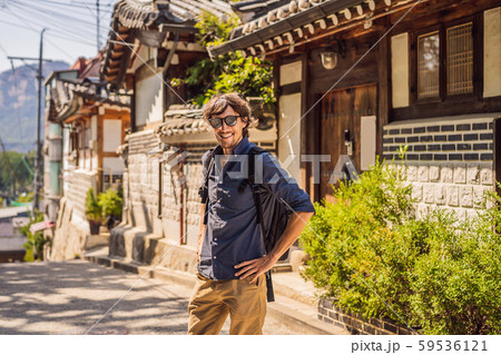 Young man tourist in Bukchon Hanok Village is one of the famous place for Korean traditional houses Young man tourist in Bukchon Hanok Village is one of the famous place for Korean traditional houses 59536121