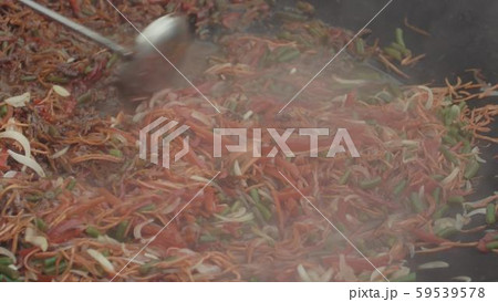 Asian mix of vegetables in liquid sauce is being stirred with a ladle in big wok Asian mix of vegetables in liquid sauce is being stirred with a ladle in big wok 59539578