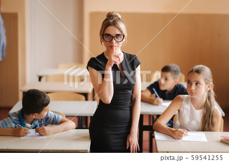 Teacher helping school kids writing test in classroom. education, elementary school, learning and 59541255