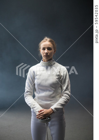 A young woman fencer with her hair in a bun standing with a sword down A young woman fencer with her hair in a bun standing with a sword down 59542035