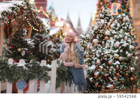 Close-up of a blonde in mittens and a scarf against the background of New Year's city trees 59542566