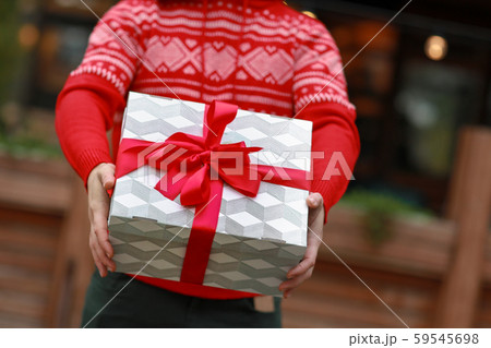 Closeup of male hands and a gift box that is decorated with a red ribbon 59545698